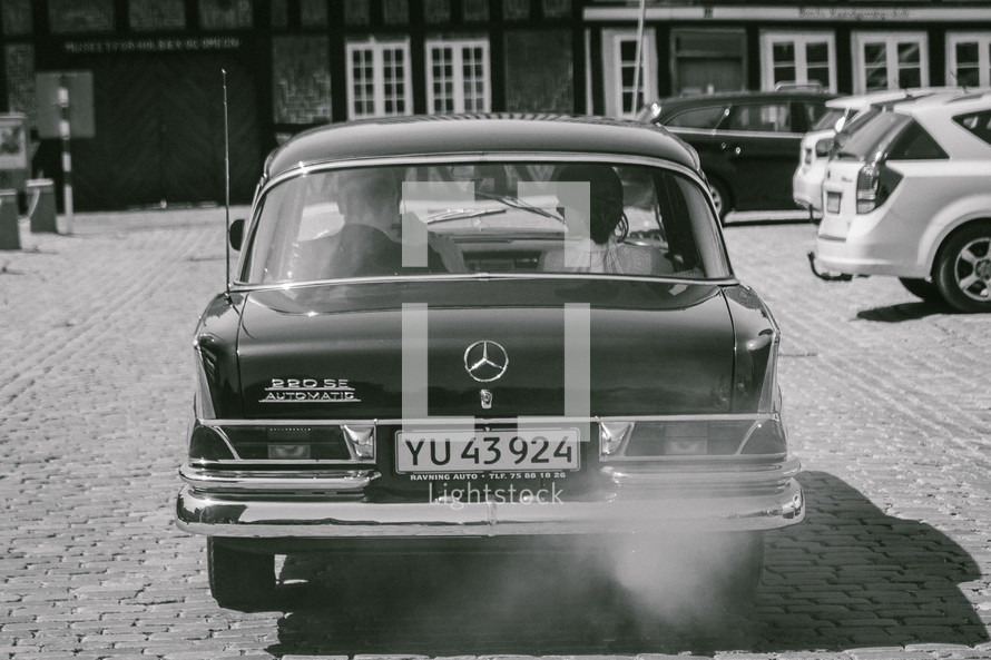 a couple in an old Mercedes driving away 