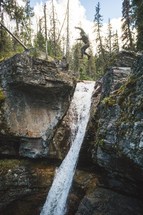 man jumping over a rock cliff and waterfall 