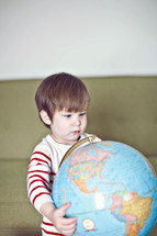 a toddler holding a globe 