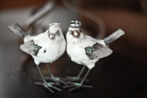 wedding bands on the heads of two bird sculptures 