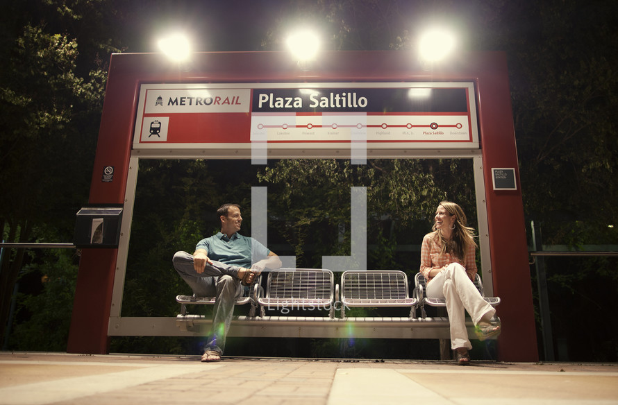 man and woman waiting at a metrorail stop 