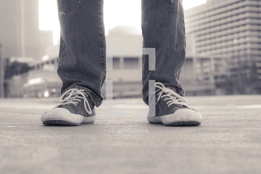 legs in sneakers standing on a city sidewalk