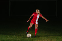 teen girl soccer player kicking a soccer ball 