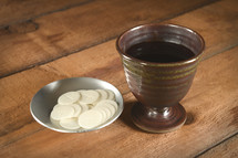 Cup of wine and communion wafers set on a communion table.