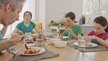 Father, mother and three children having a breakfast of pancakes with fruits
