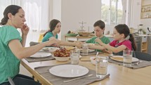Mother and three kids eating breakfast of pancakes and fruits