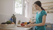 Teenage girl working cutting fruit for breakfast in the kitchen