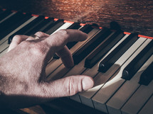 a hand playing notes on a piano keyboard