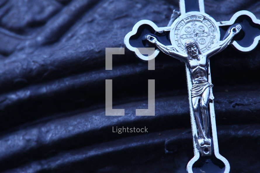 silver crucifix necklace on blue cloth