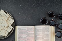 open Bible, unleavened bread, and communion wine cups 