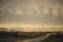 Rainbow in stormy clouds over a wet highway.
