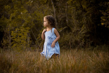 toddler girl standing in tall grass