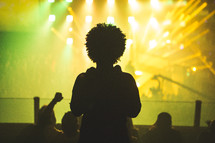 Silhouette of a boy with bright yellow stage lights shining on him.