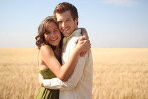 a couple hugging in a field of grains 