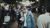 a woman walking through a crowd at a festival carrying a hamburger 