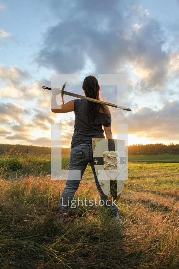 Warrior woman spies the land, resting a double-handle sword and a shield by her side. 