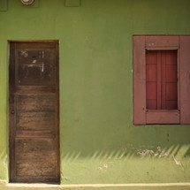 wood door and window on a green exterior wall 