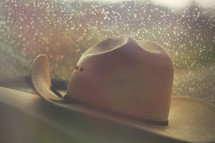 a hat on a dashboard with raindrops on the windshield 
