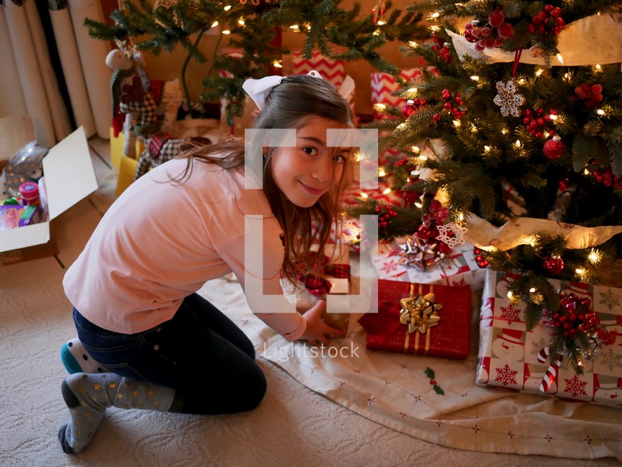 a girl looking at gifts under a Christmas tree 