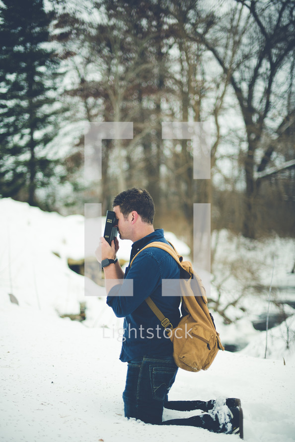 a man kneeling in snow praying 