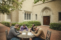 Men's BIble study group praying at table
