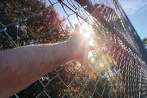 hand grabbing a metallic fence, feeling free