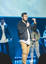 worship leaders standing on stage holding microphones 
