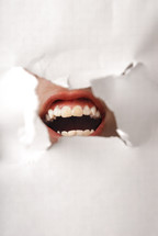 Screaming human mouth behind the damaged paper