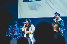 worship leaders standing on stage holding microphones 