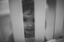 face of a young girl looking into a crib at her baby sister 