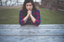 A woman praying outdoors. 