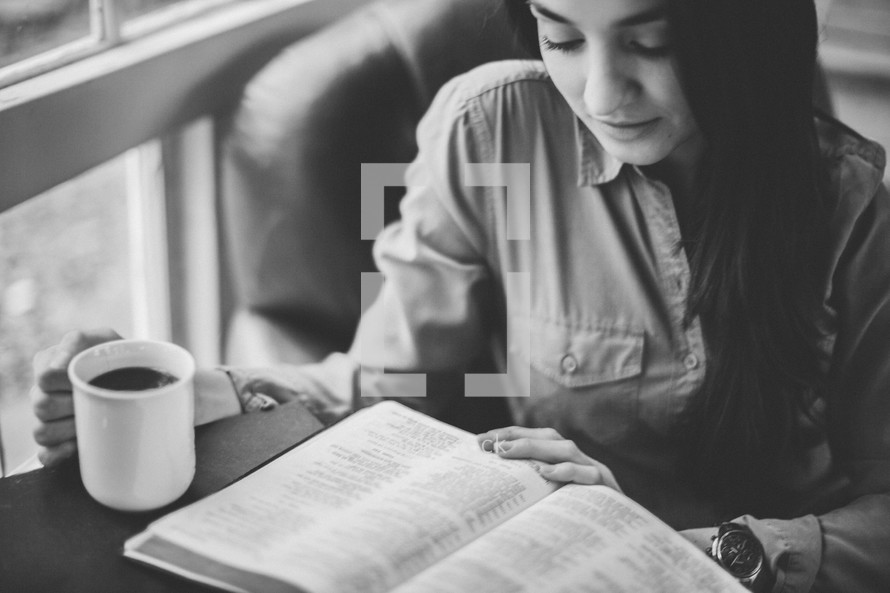 A woman reading a Bible and drinking coffee