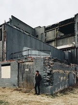 man standing outdoors in front a collapsing building 