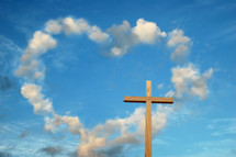 clouds in the shape of a heart in a blue sky and a wood cross