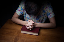 a woman in prayer over a Bible 