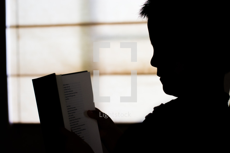 silhouette of a child reading a book 