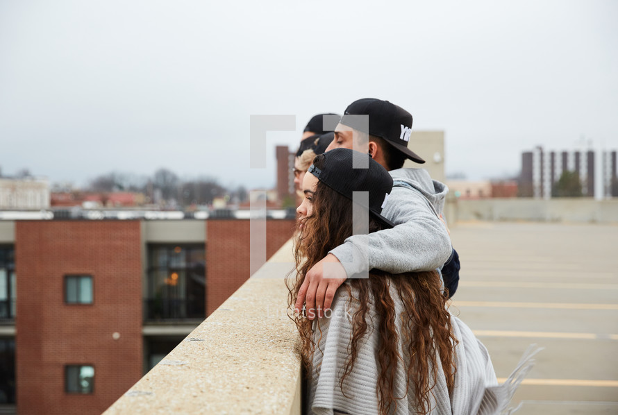 group of young people looking over a railing on a parking deck 