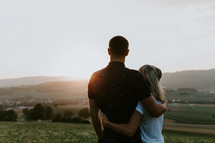 couple hugging on a hill at sunset 