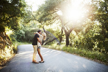 couple standing in the middle of a country road hugging