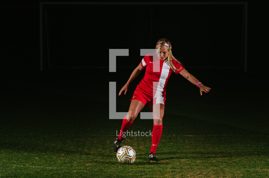 teen girl soccer player kicking a soccer ball 