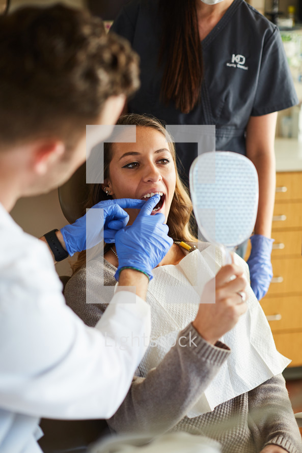 a dentist and dental hygienist with their patient in an exam room 