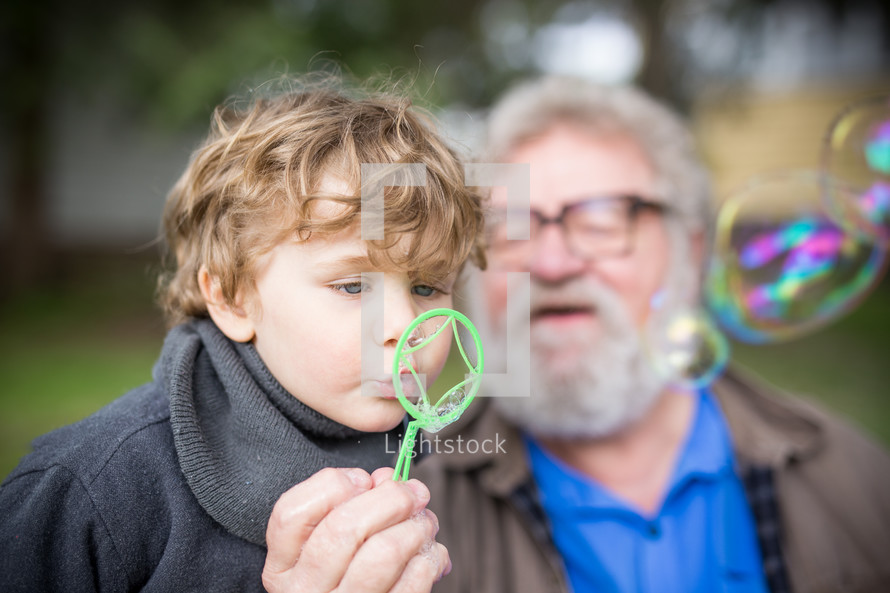 grandfather and grandson blowing bubbles 