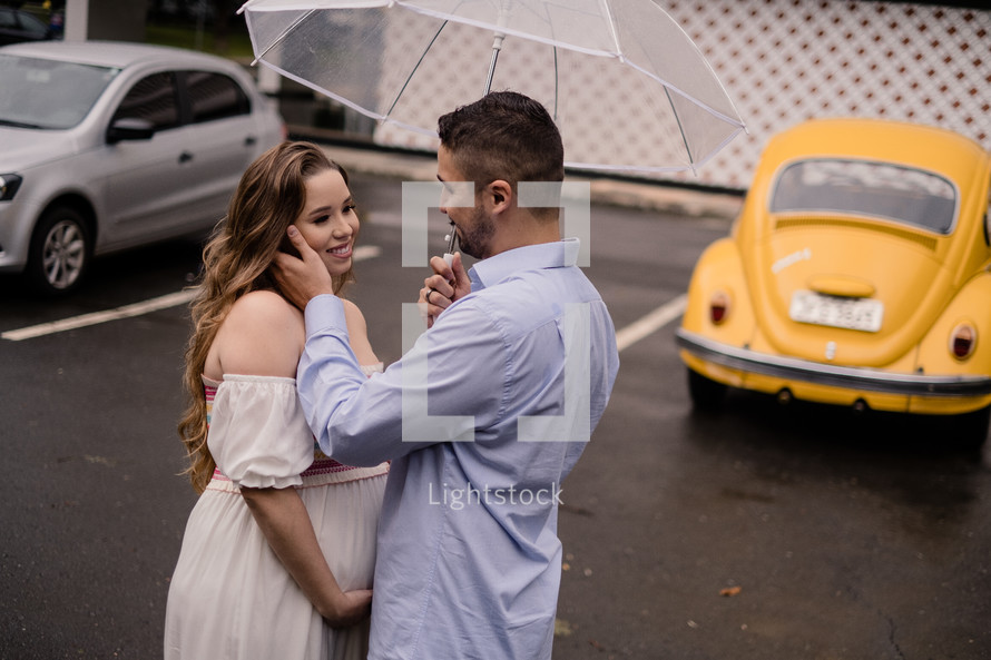 portrait of an expecting couple standing under an umbrella 