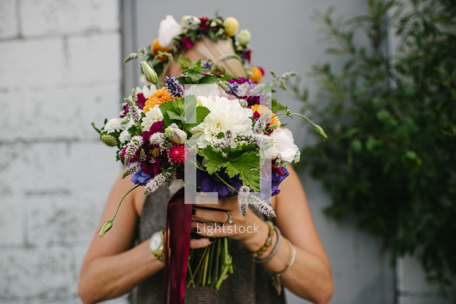 a woman holding a bouquet of flowers in front of her face 