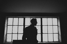 The profile of a groom in front of windows in a warehouse