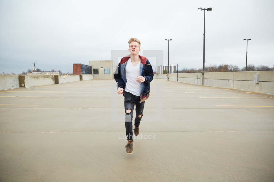 teen boy running in a parking deck 