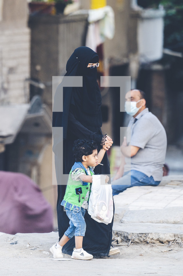 Muslim mother walking with her child through the streets of a city in Egypt 