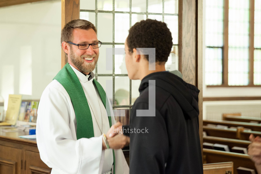 a priest greeting a teen boy 