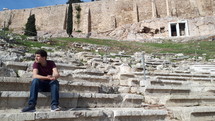 man sitting in ancient coliseum in Greece 