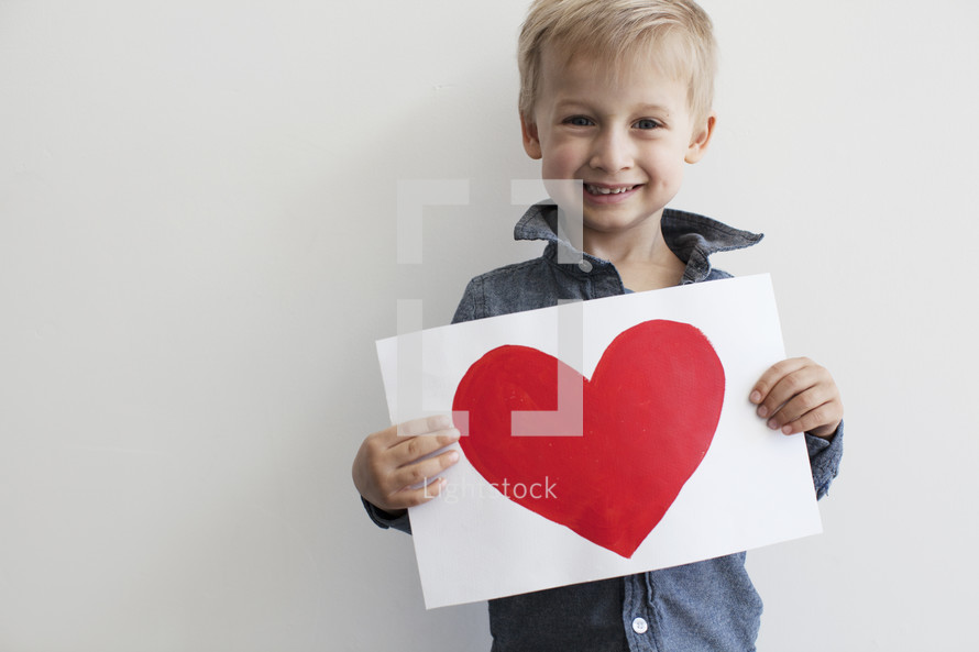 toddler boy holding a painting of a red heart 